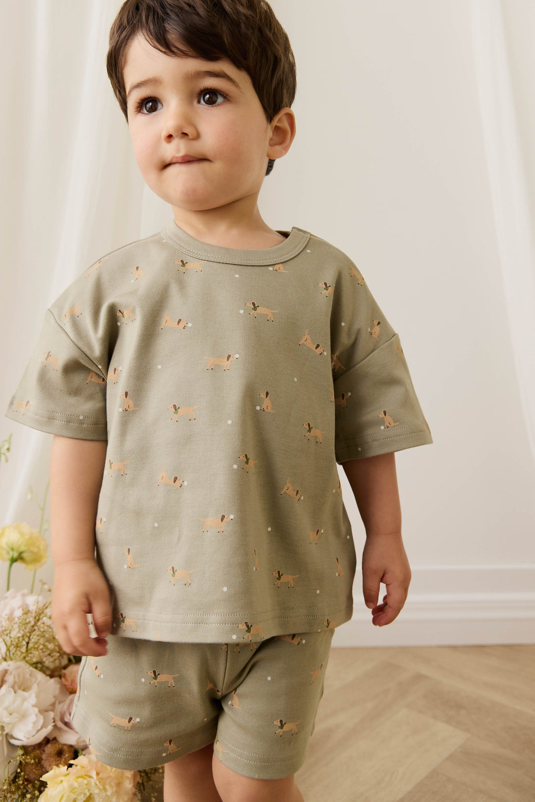 Child wearing a green outfit with animal prints in a home setting