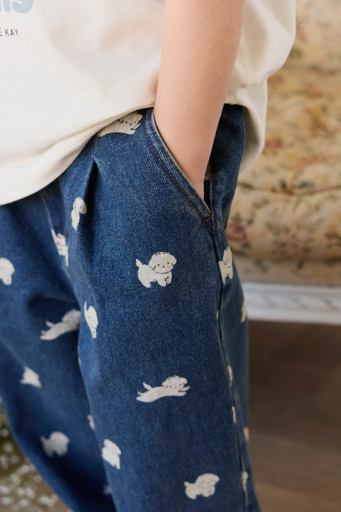 Blue denim pants with white dog prints worn by a person, blurred background