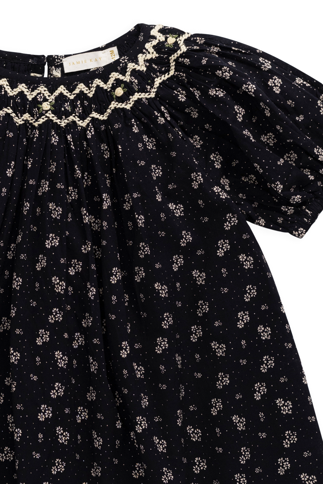 Black dress with floral pattern and ruffled neckline on a white background
