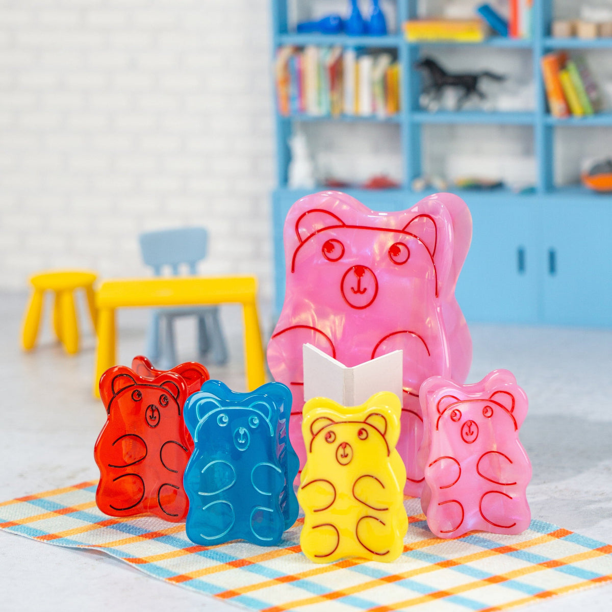 Colorful gummy bear-shaped molds on a checkered mat with a child's room in the background.