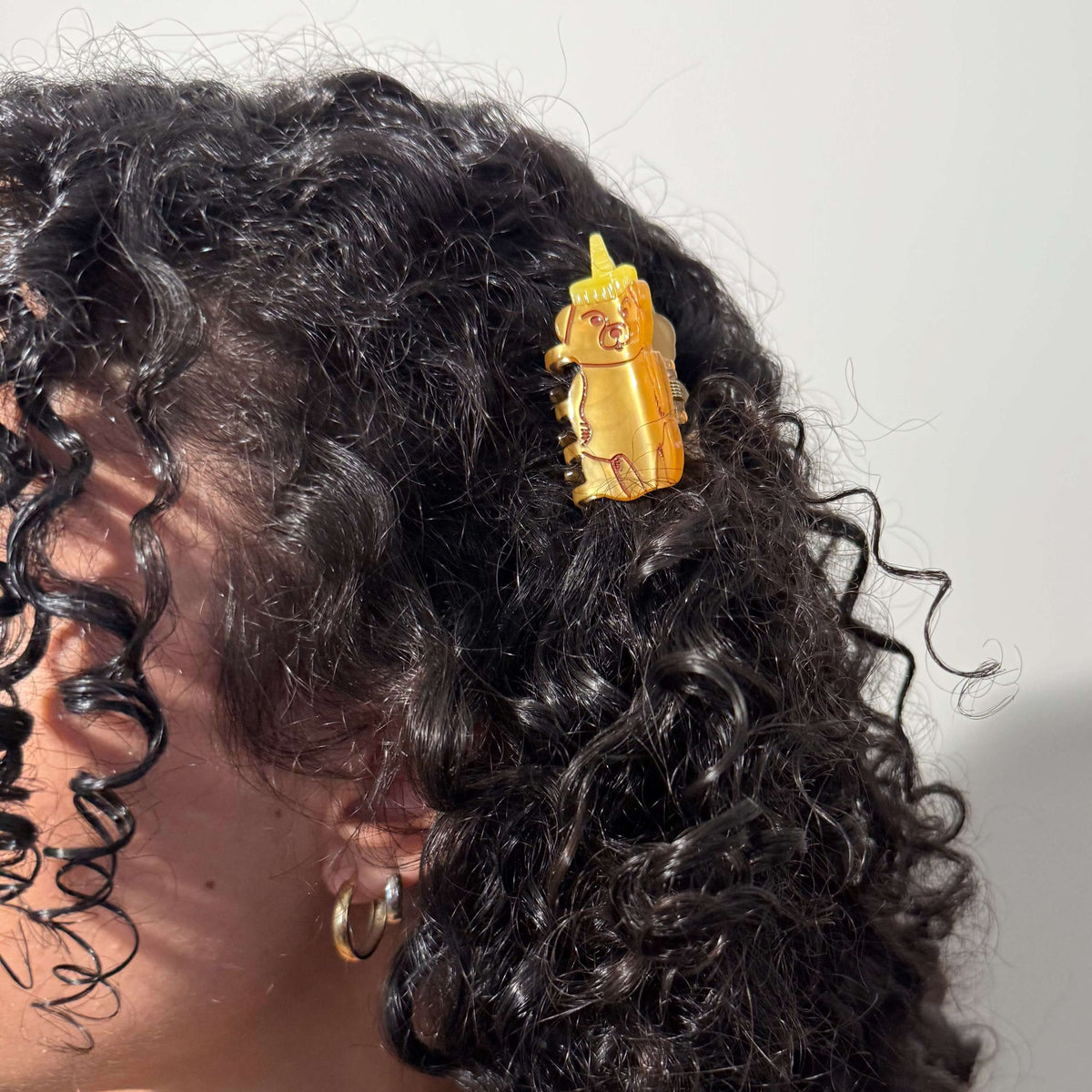 Close-up of a person's hair with a gold hair accessory featuring a bear design.