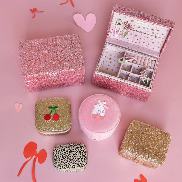 Collection of decorative jewelry boxes on a pink background with heart and bow designs.