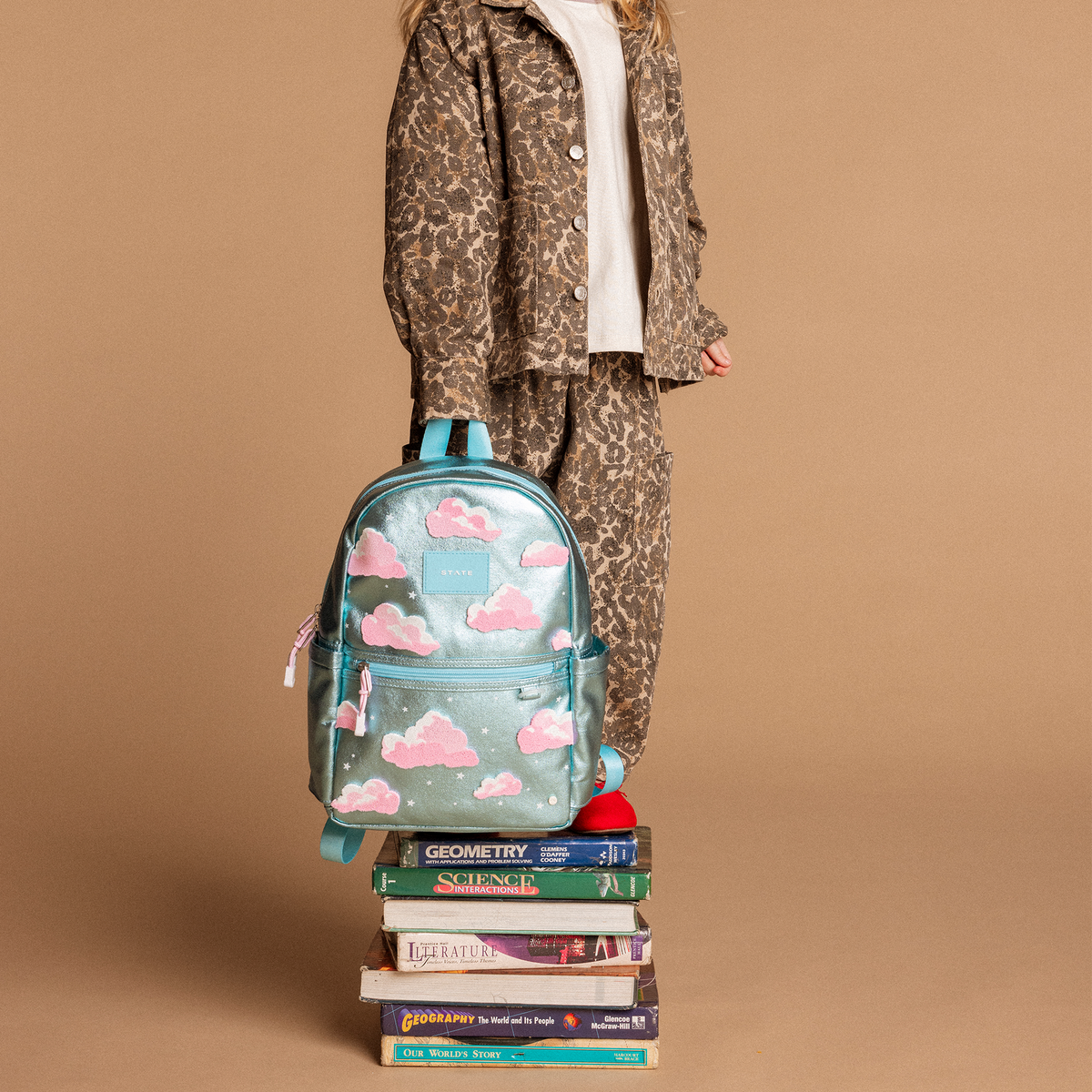 Person wearing a leopard print outfit with a backpack on a brown background