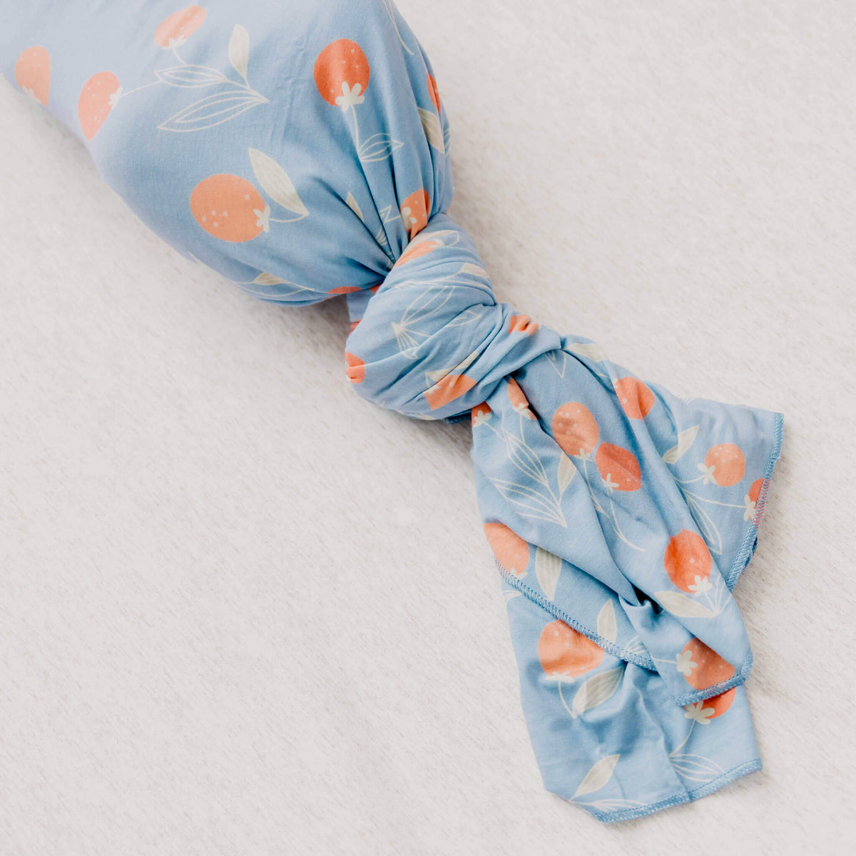 Blue fabric with orange and white floral pattern on a light gray background