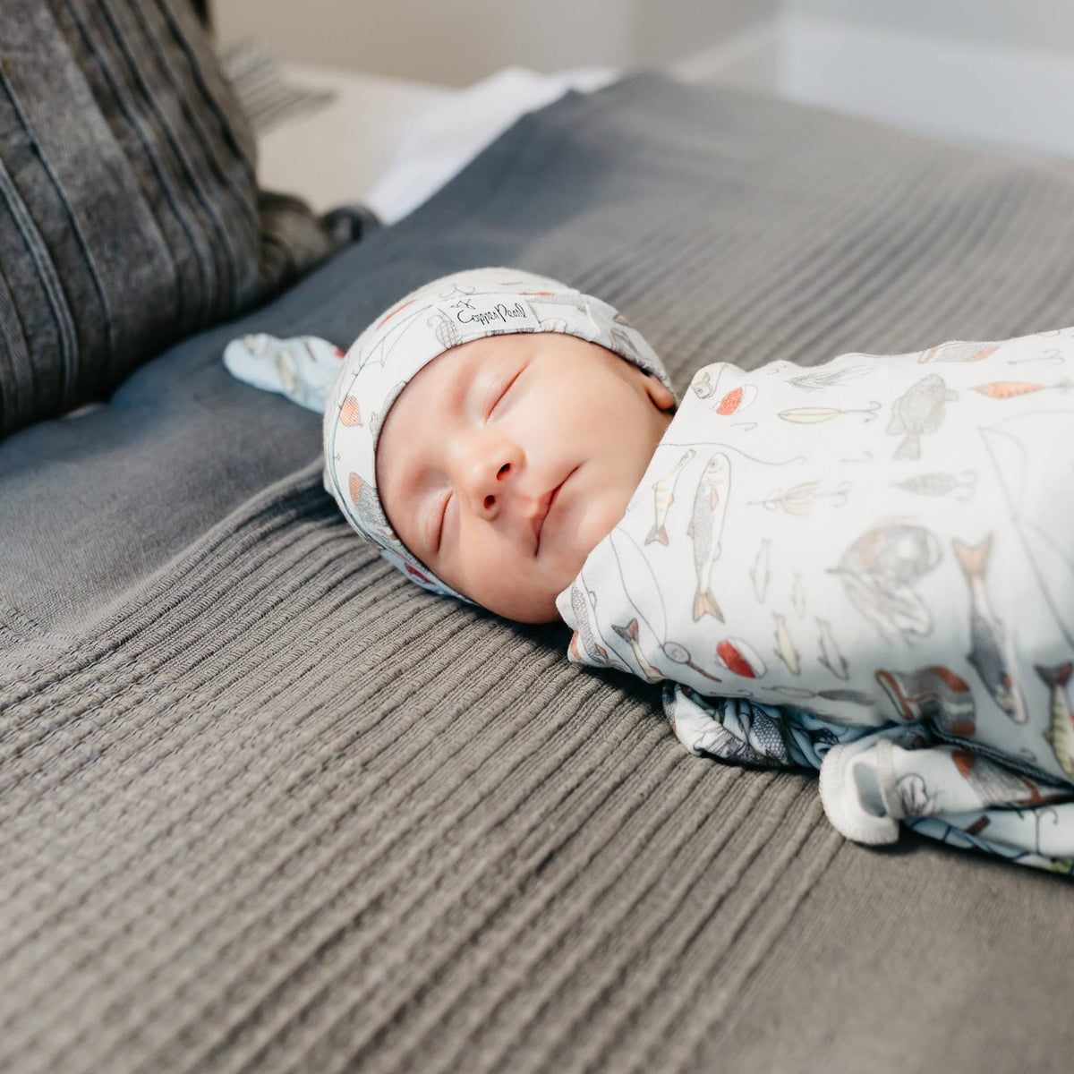Newborn baby swaddled in a blanket with animal patterns on a textured surface.