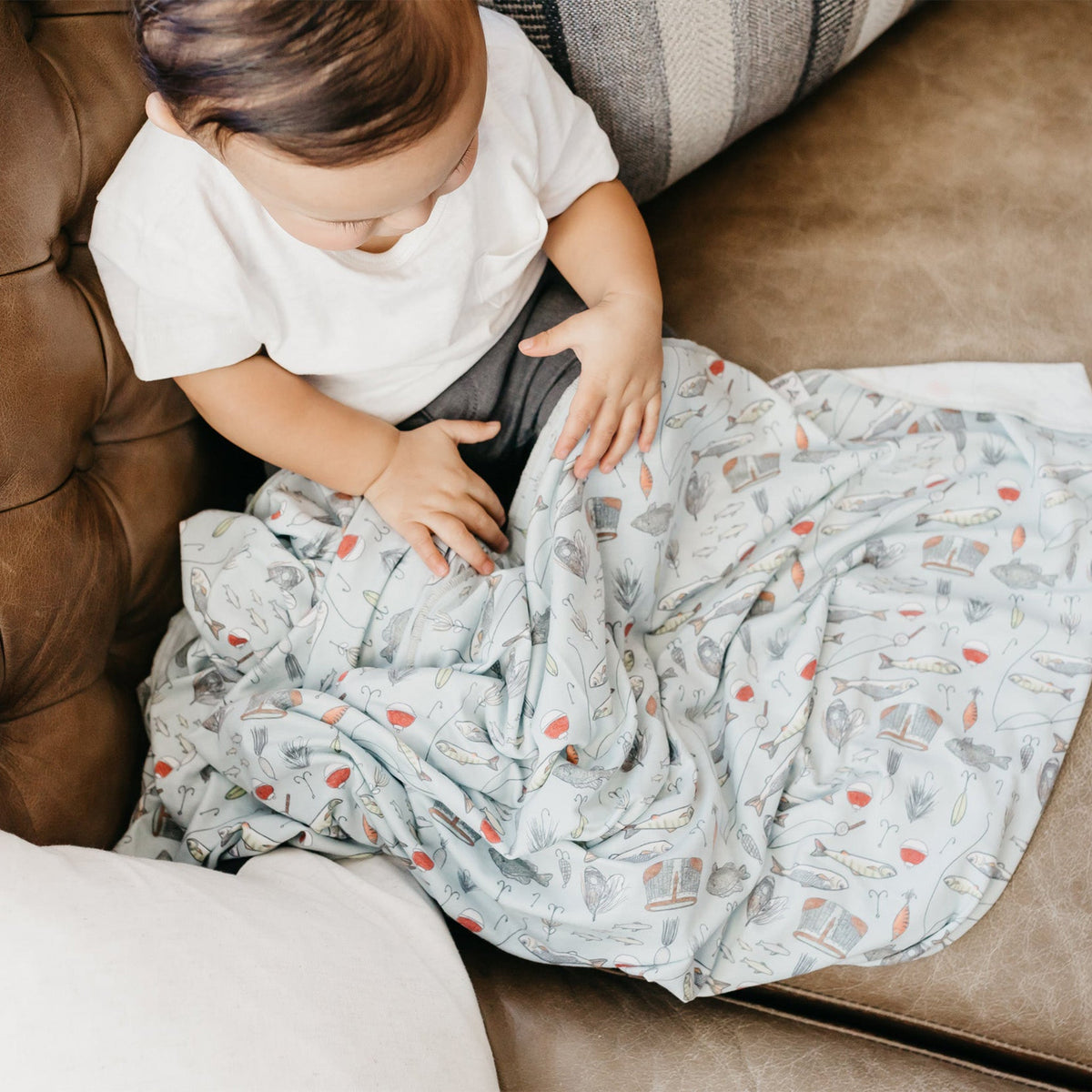 Child playing with a patterned blanket on a couch