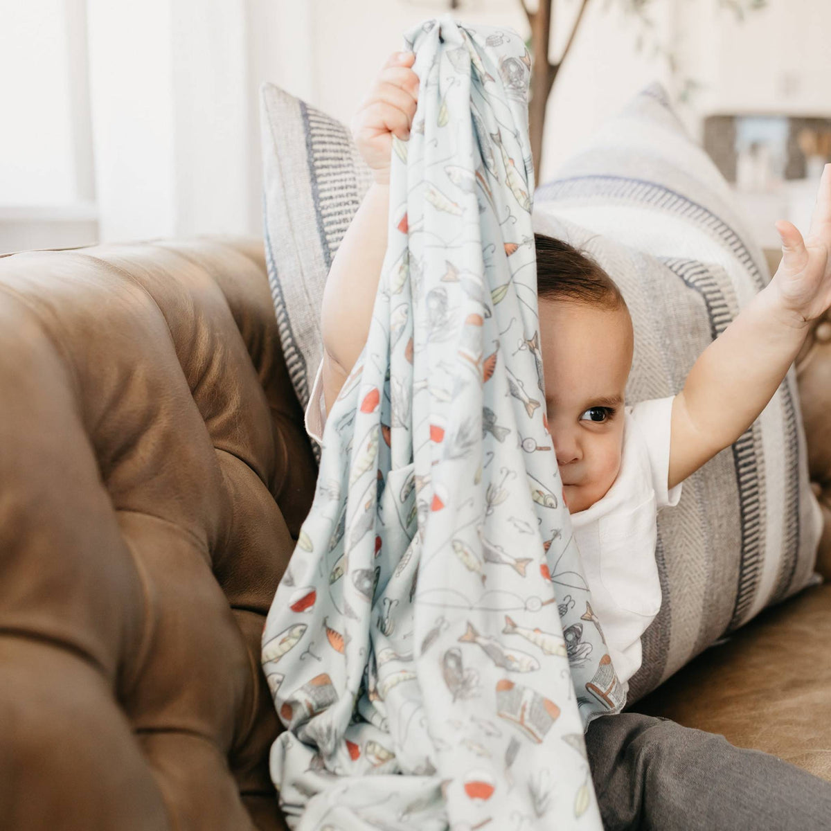 Baby holding a patterned blanket in a cozy living room setting