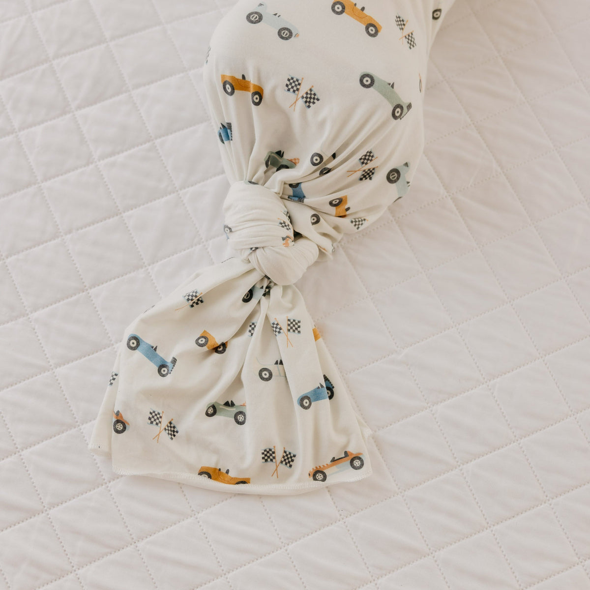 Baby headband with car pattern on a white quilted surface