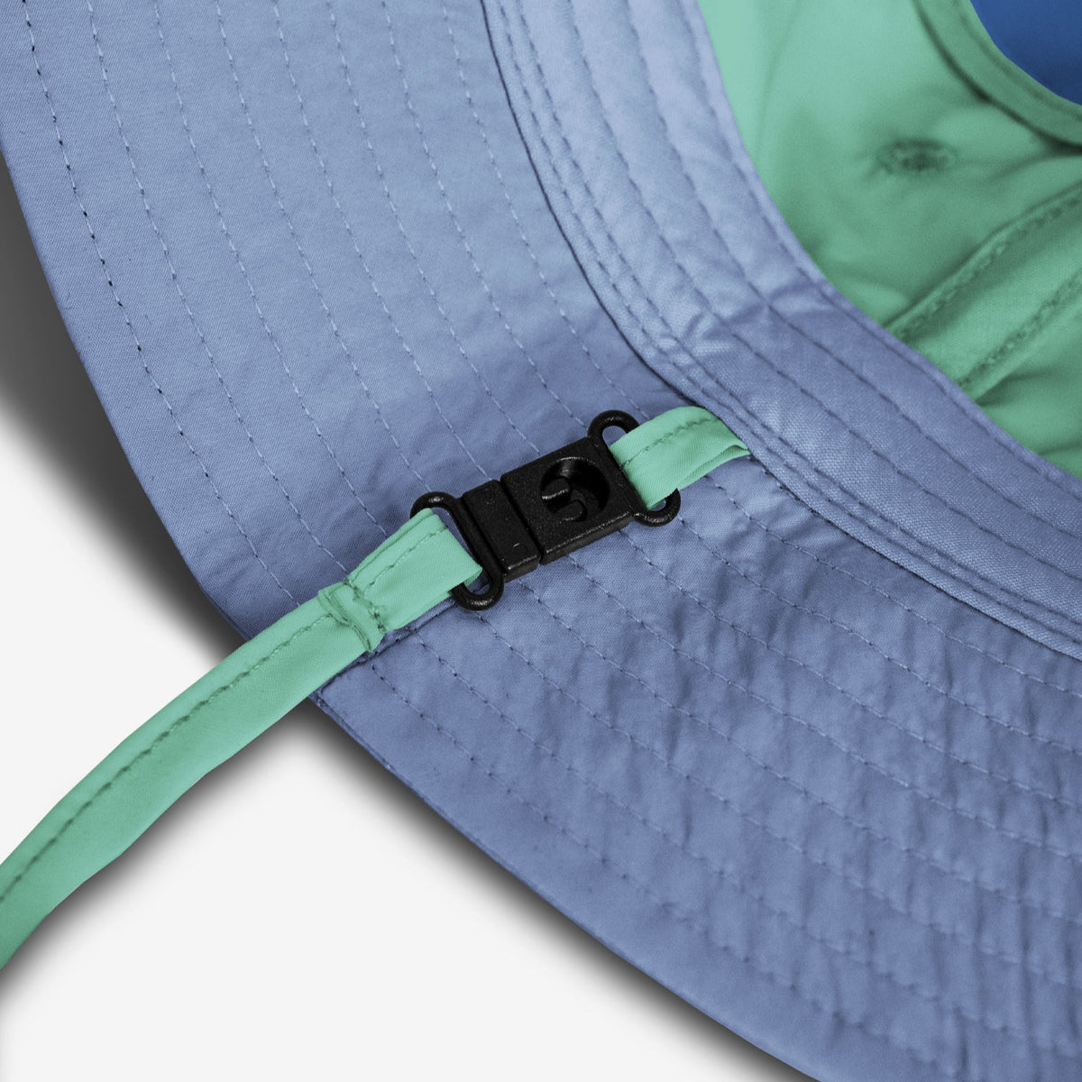 Close-up of a blue cap with a green strap and buckle on a white background