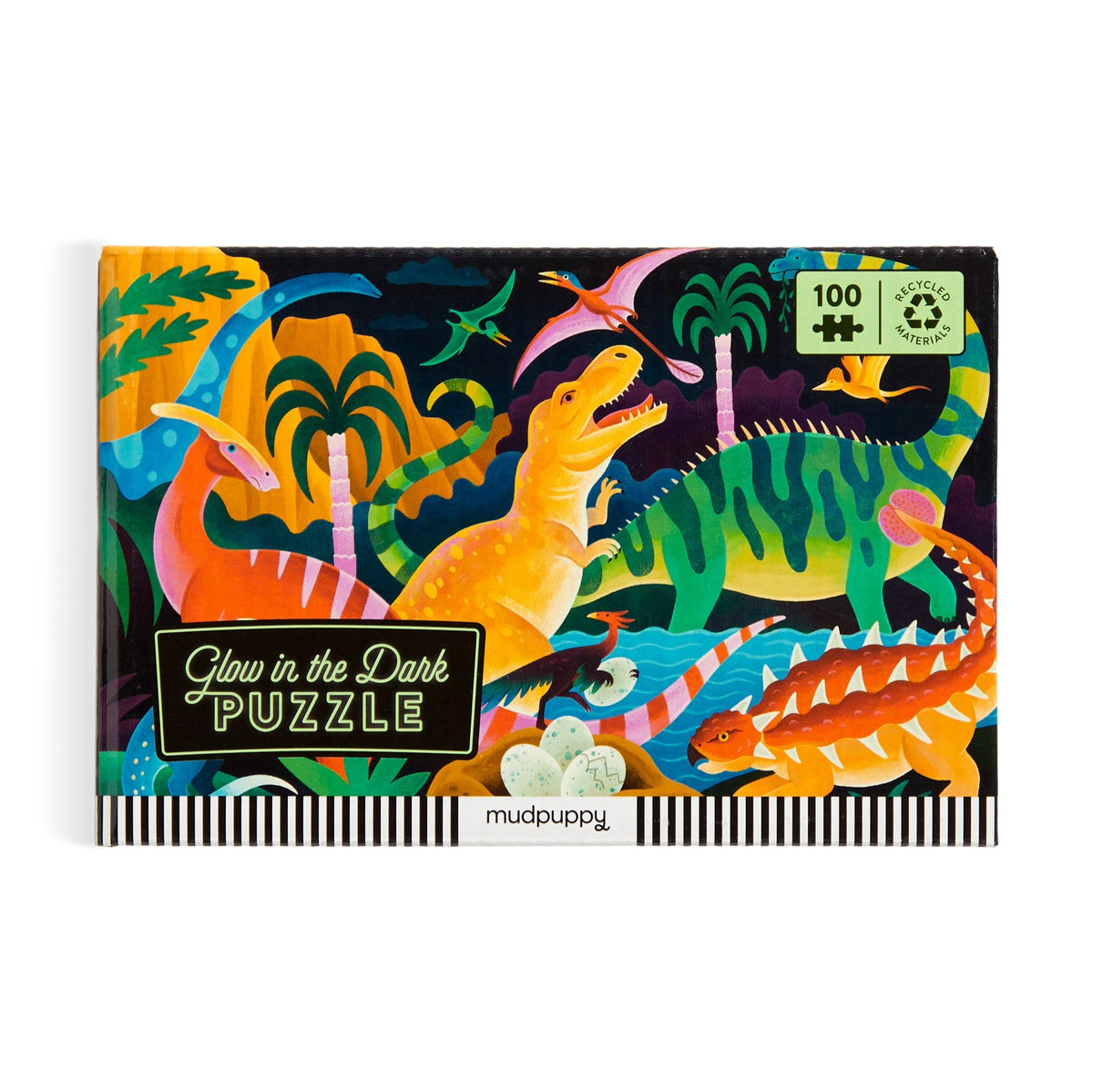 A product photo of the Dinosaur Park 100 Piece Glow in the Dark Puzzle by Mudpuppy box against a white background, featuring illustrated prehistoric dinosaurs and a "Glow in the Dark PUZZLE" label on the front.