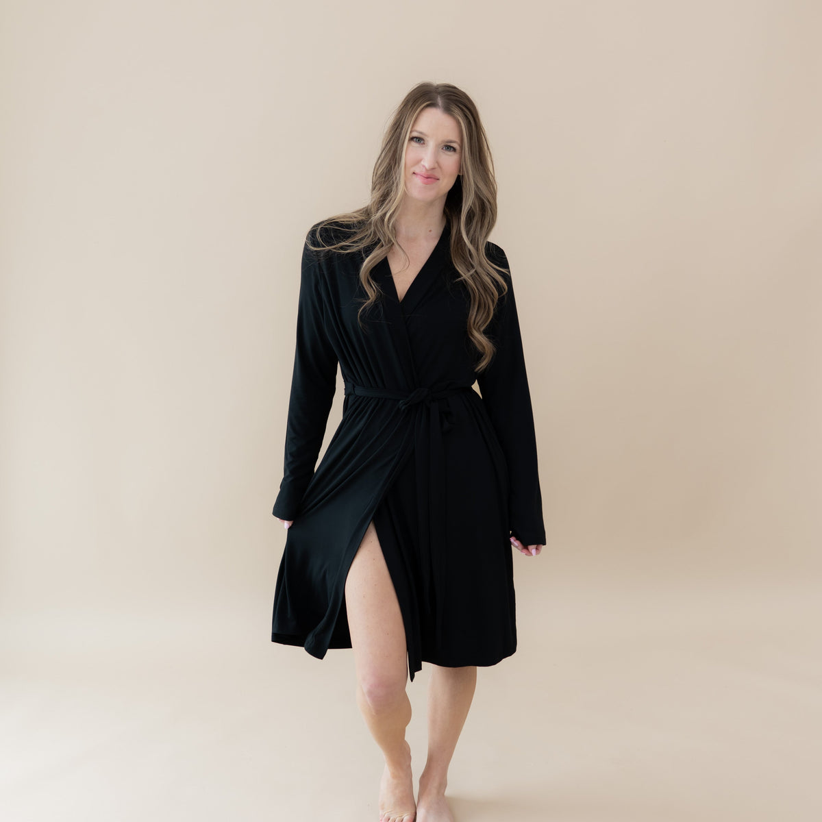 Woman wearing a black robe against a beige background