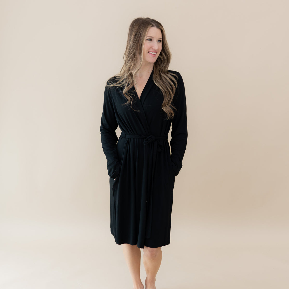 Woman wearing a black dress against a beige background