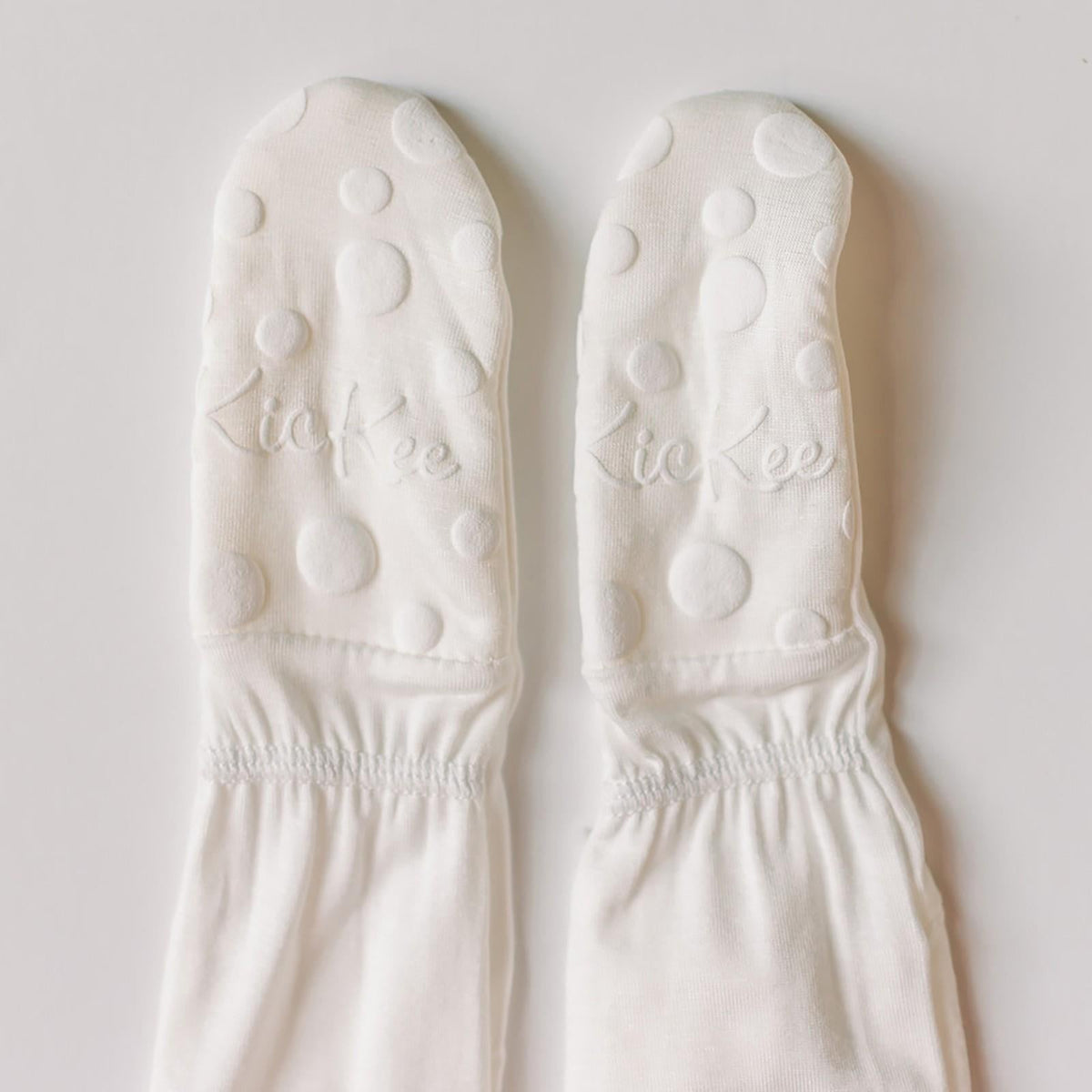 Pair of white socks with bubble pattern and 'kie kee' branding on a light gray background