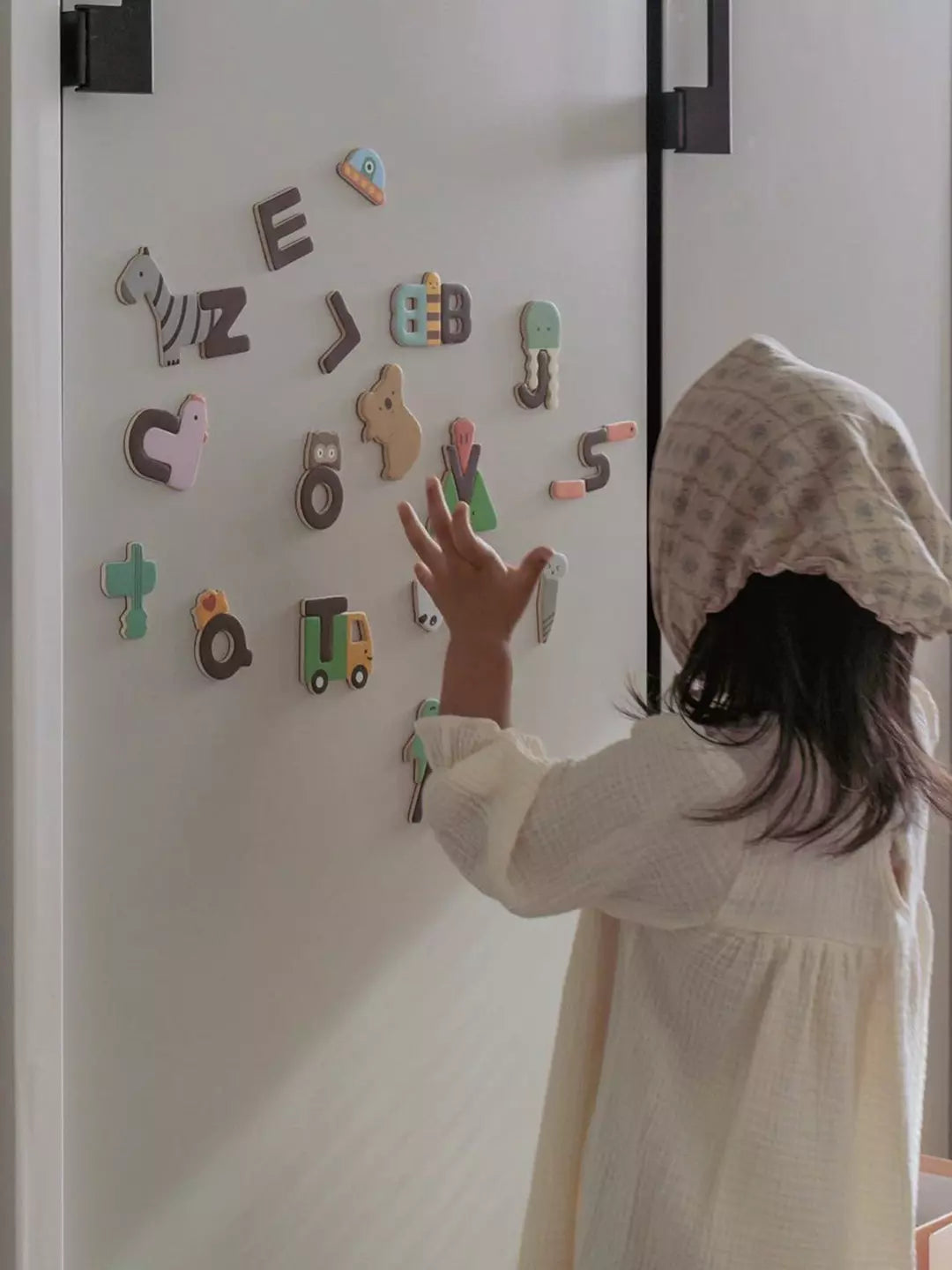 Child playing with colorful magnetic letters on a refrigerator door