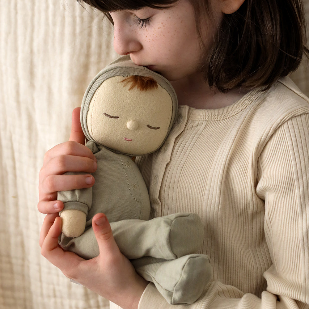 Person holding a small plush toy against a neutral background