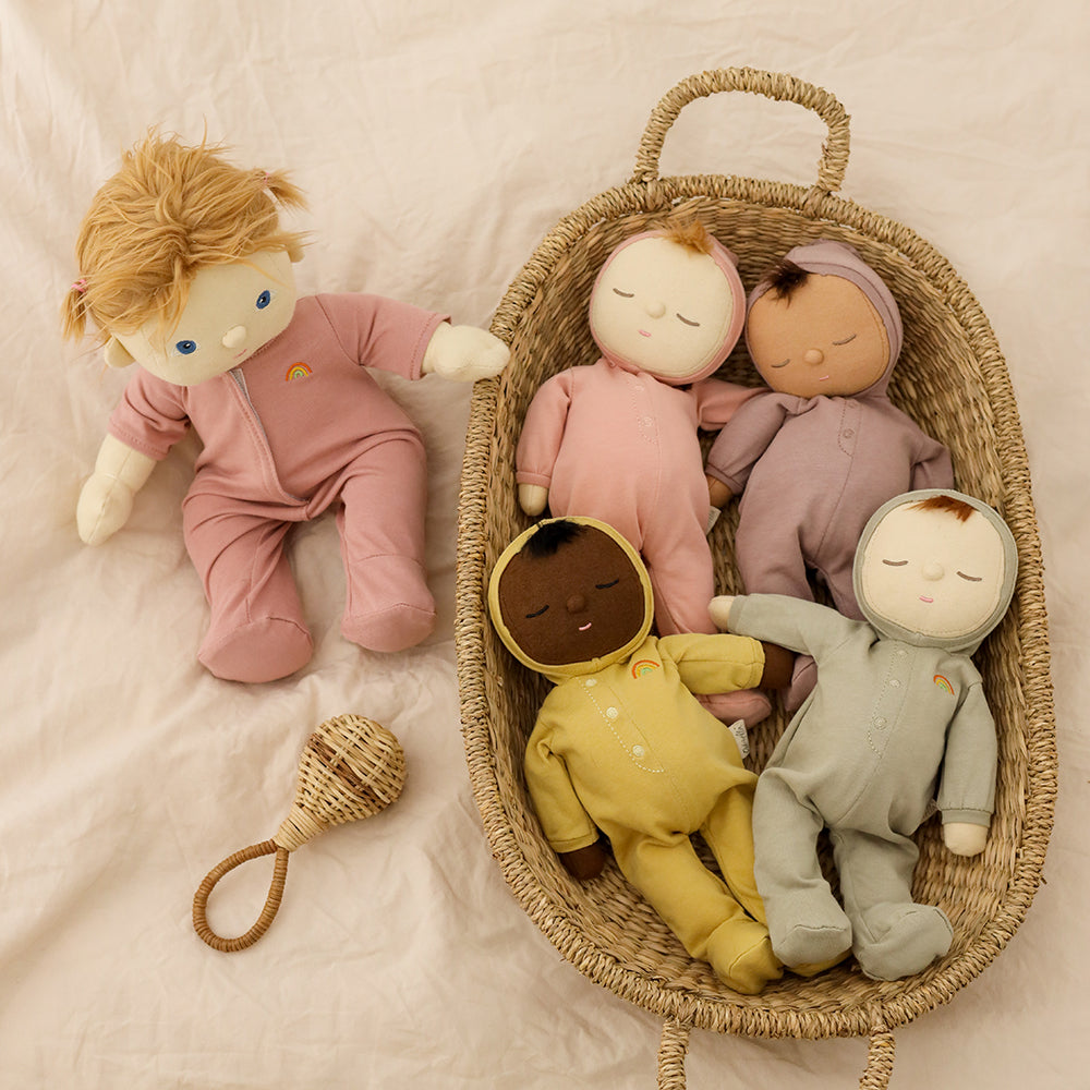 Set of dolls in a wicker basket with a rattle on a soft surface