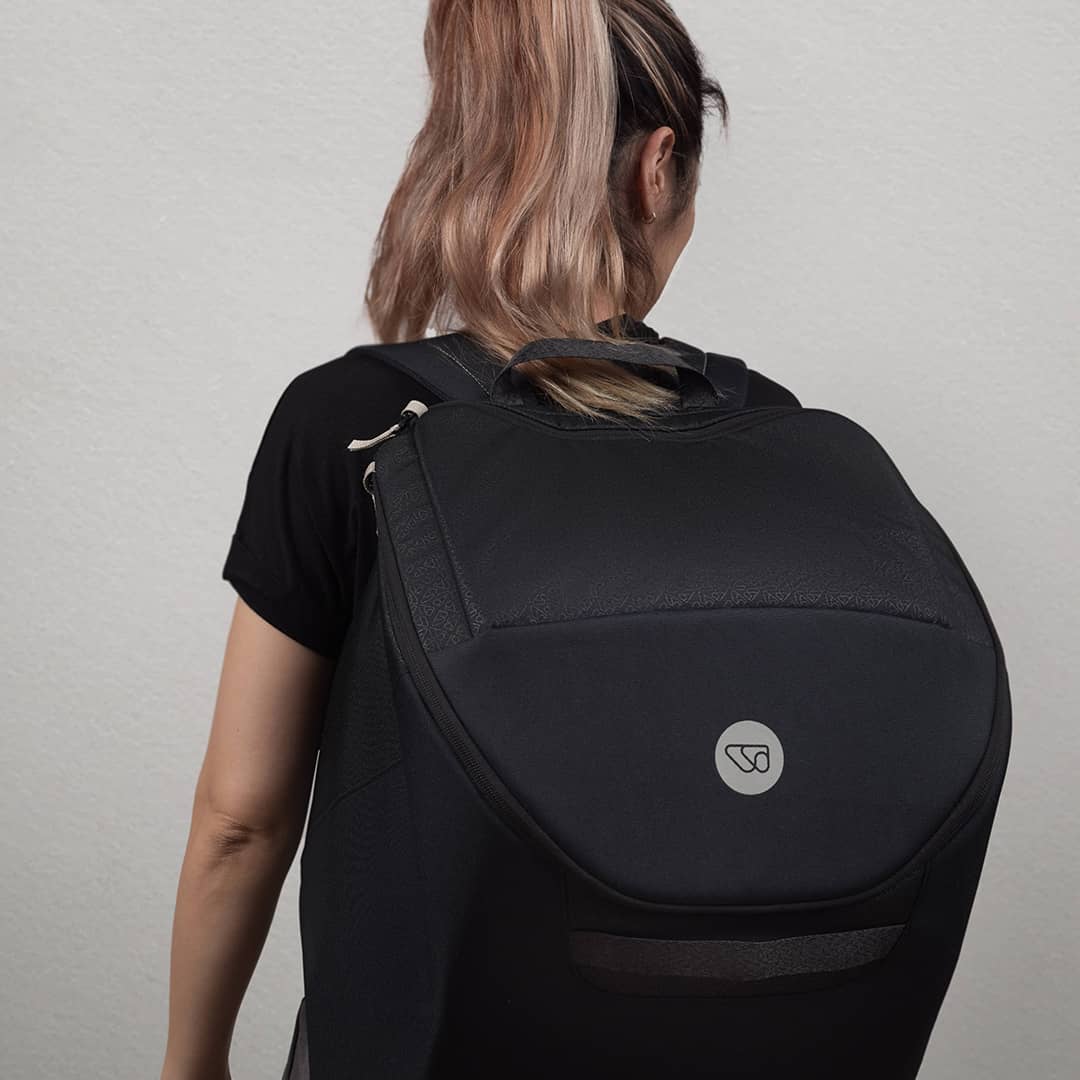Person wearing a black backpack with a visible brand logo on a plain background