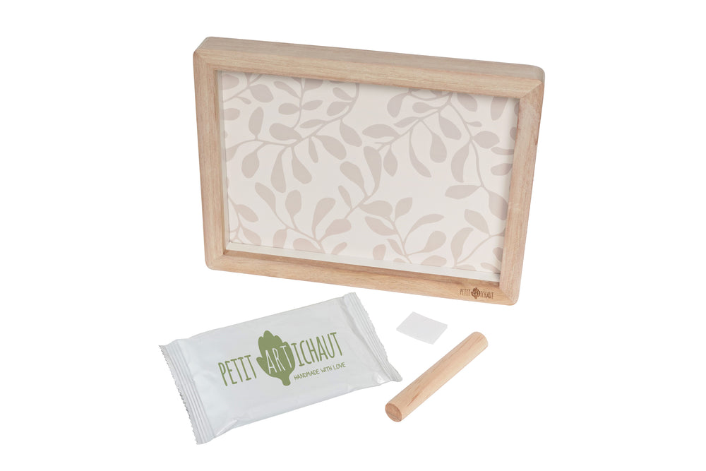Wooden frame with patterned paper, Petit Pitcheau packaging, and wooden tool on a white background