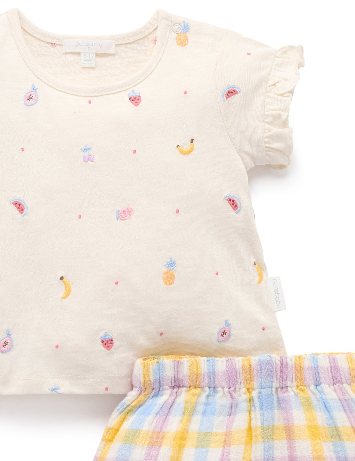 Beige top with fruit patterns and plaid shorts on a white background