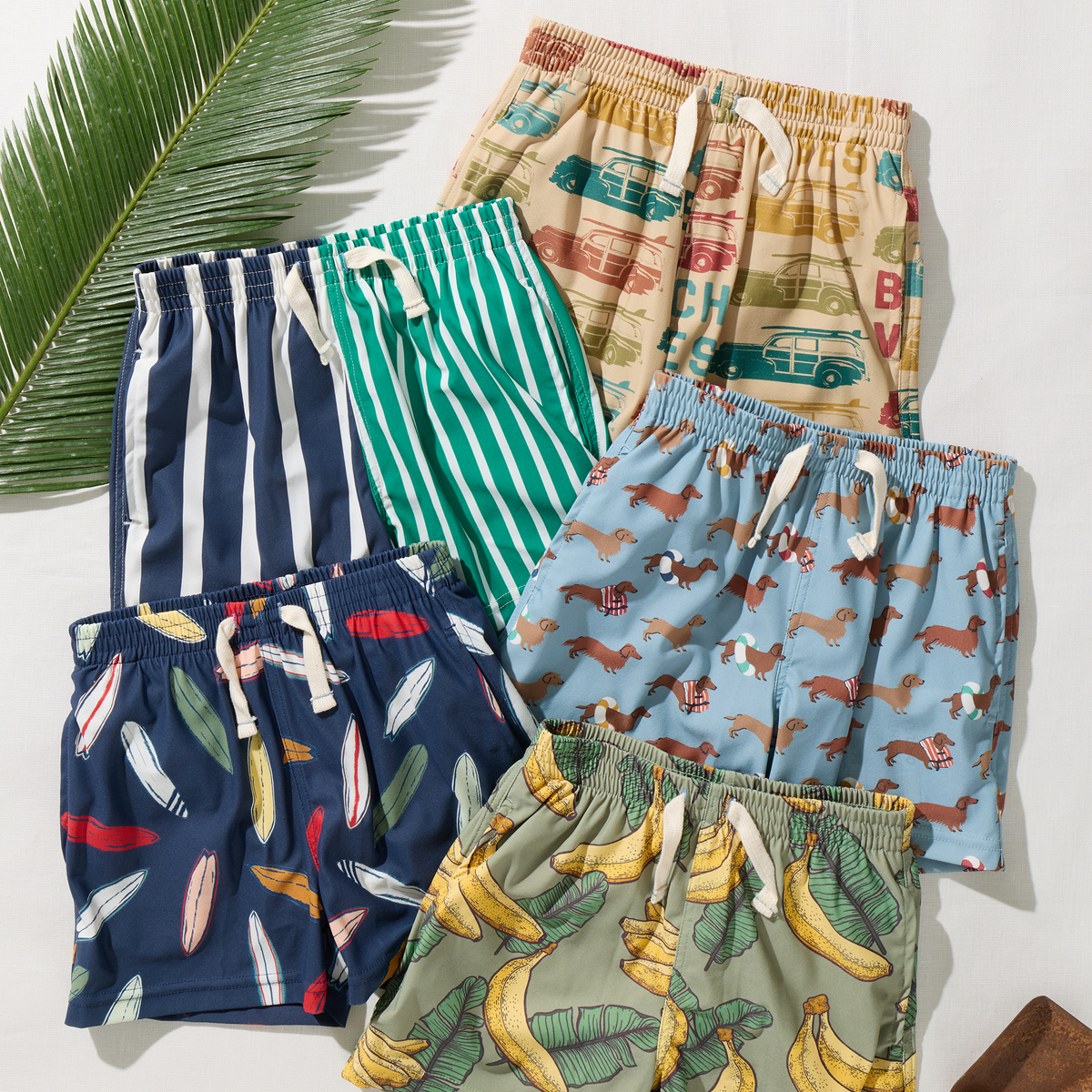 Collection of colorful children's shorts with various patterns on a light background.