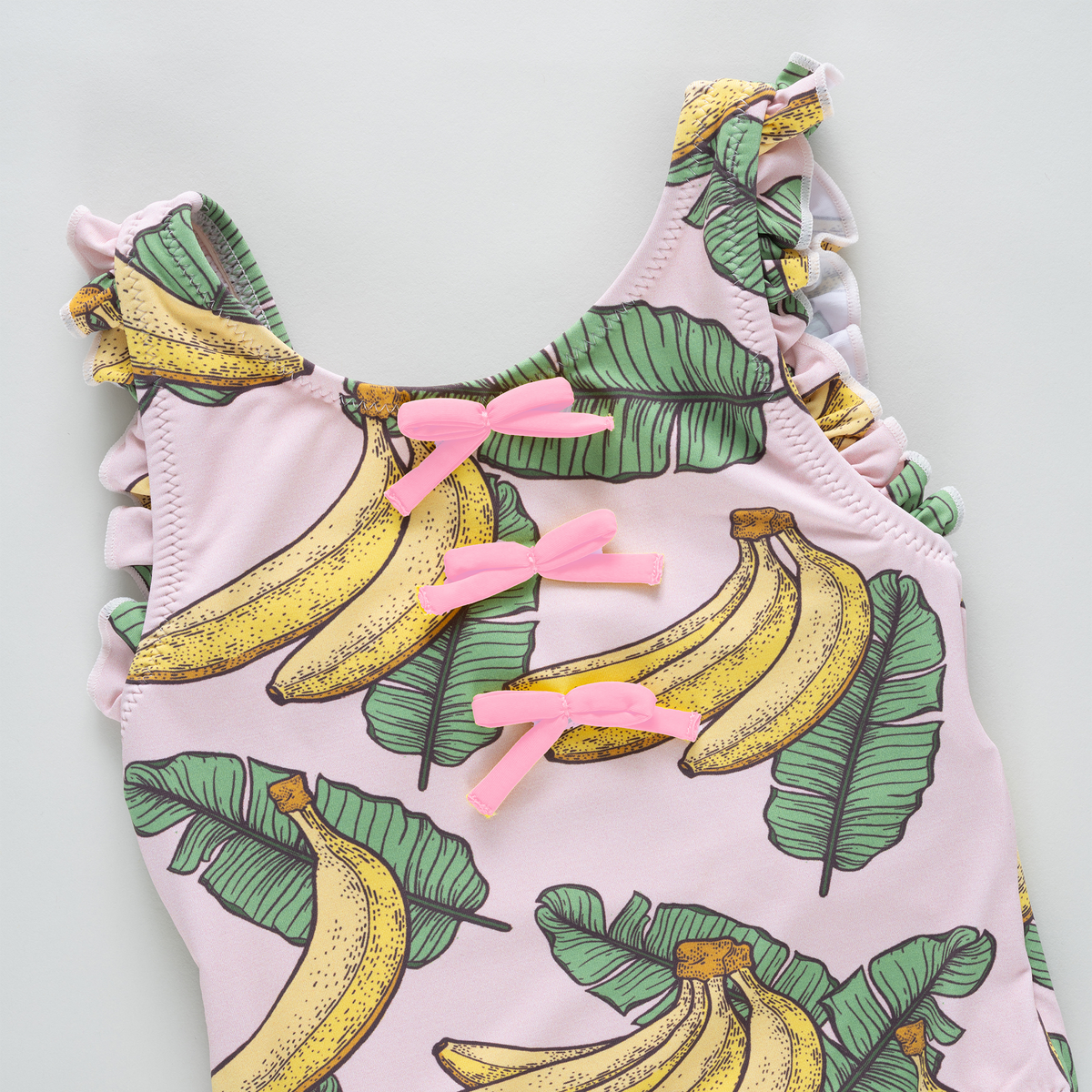 Pink tank top with banana and leaf pattern on a light gray background