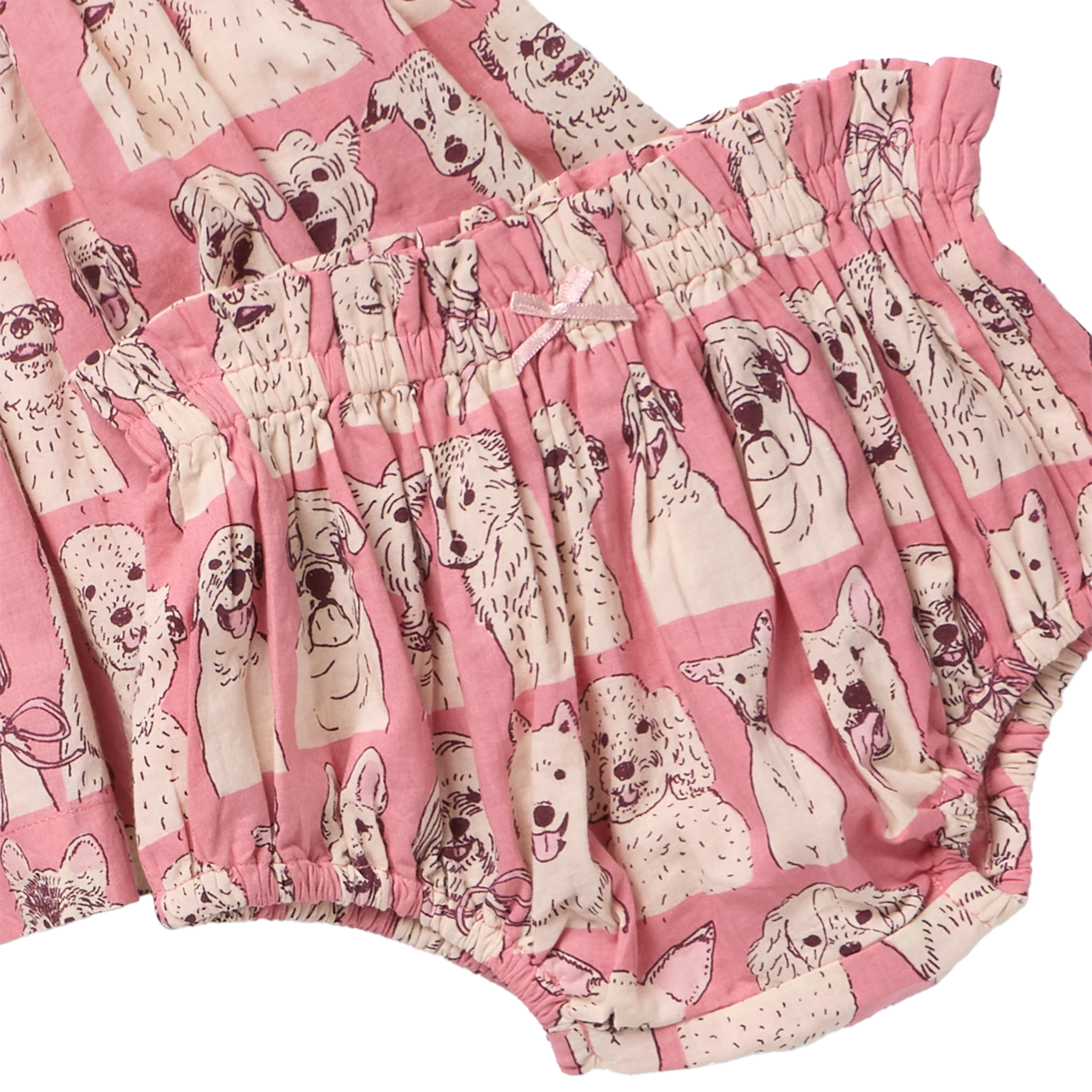 Pink ruffled bloomers with an all-over print of cartoon dog faces, shown alongside a matching top in the same fabric.