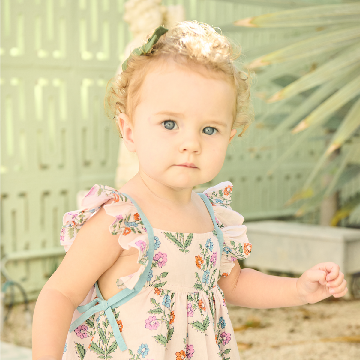 Young girl in a floral dress standing outdoors with a blurred background