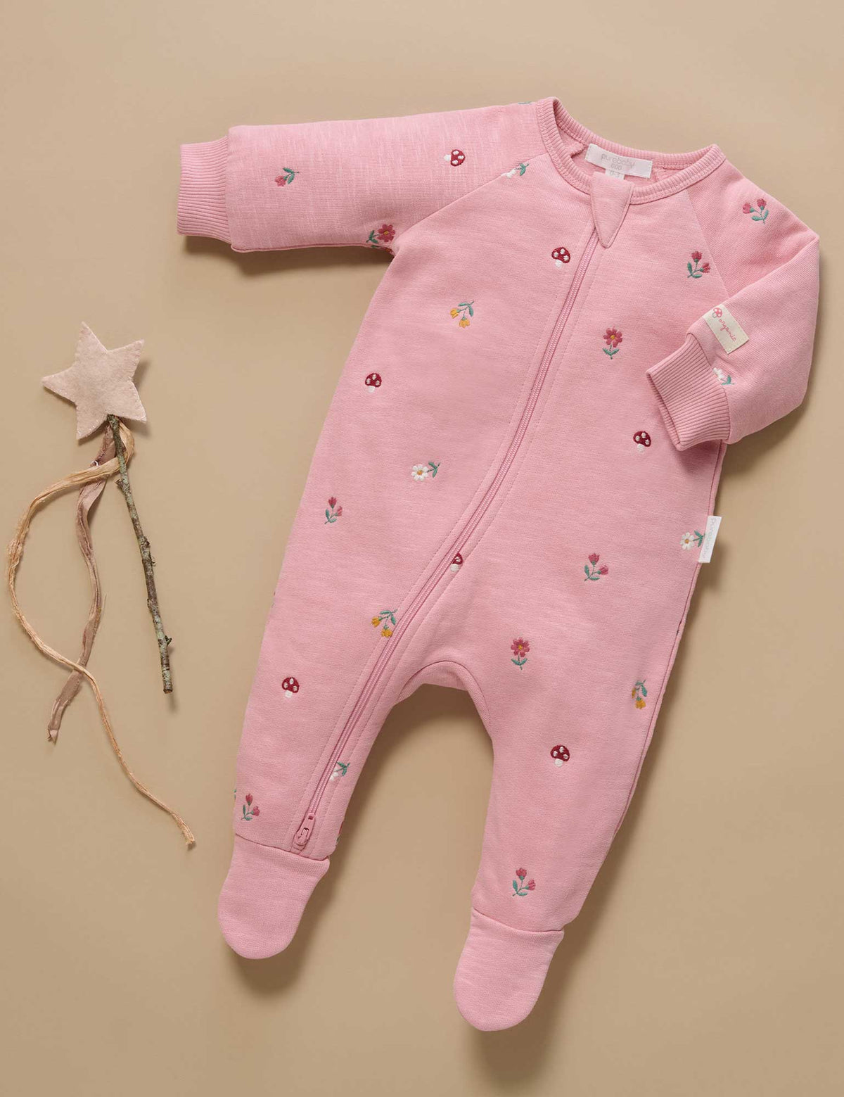 Pink baby onesie with floral patterns on a beige background