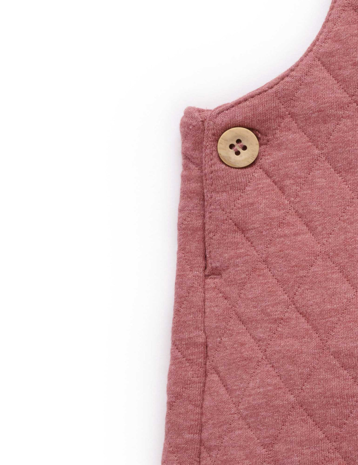 Quilted pink garment with a button on a white background