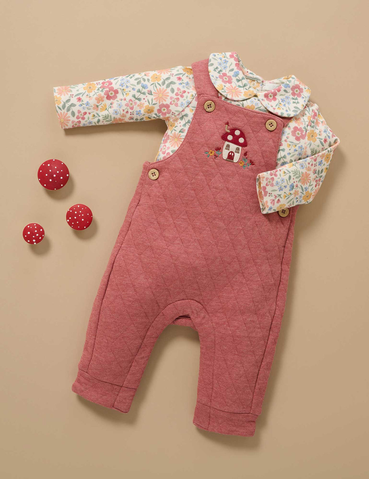 Pink baby romper with floral shirt on a beige background