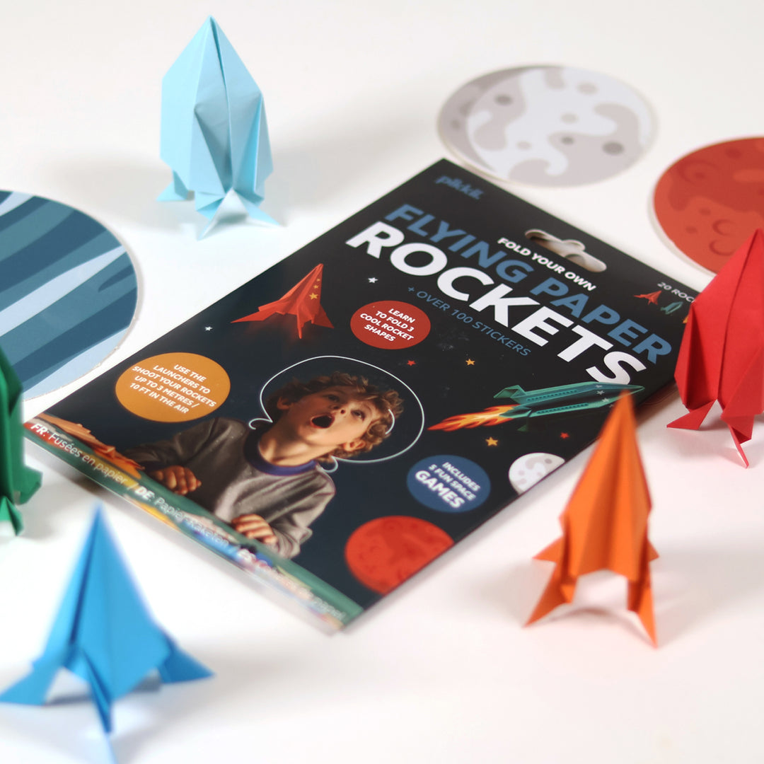 Book titled 'Flying Paper Rockets' with paper rockets and space-themed items on a white background