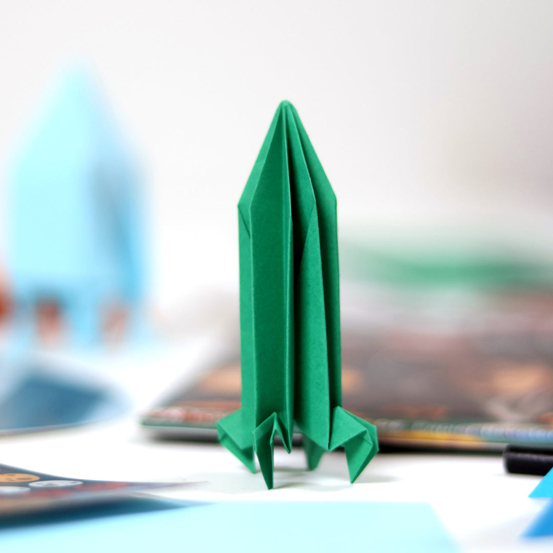 Green origami rocket ship on a blurred background
