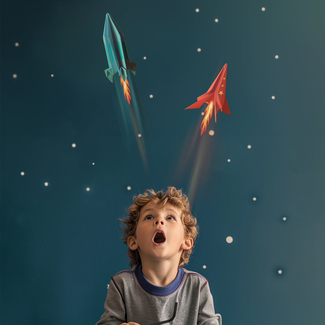 Child looking up at toy rockets against a starry night sky
