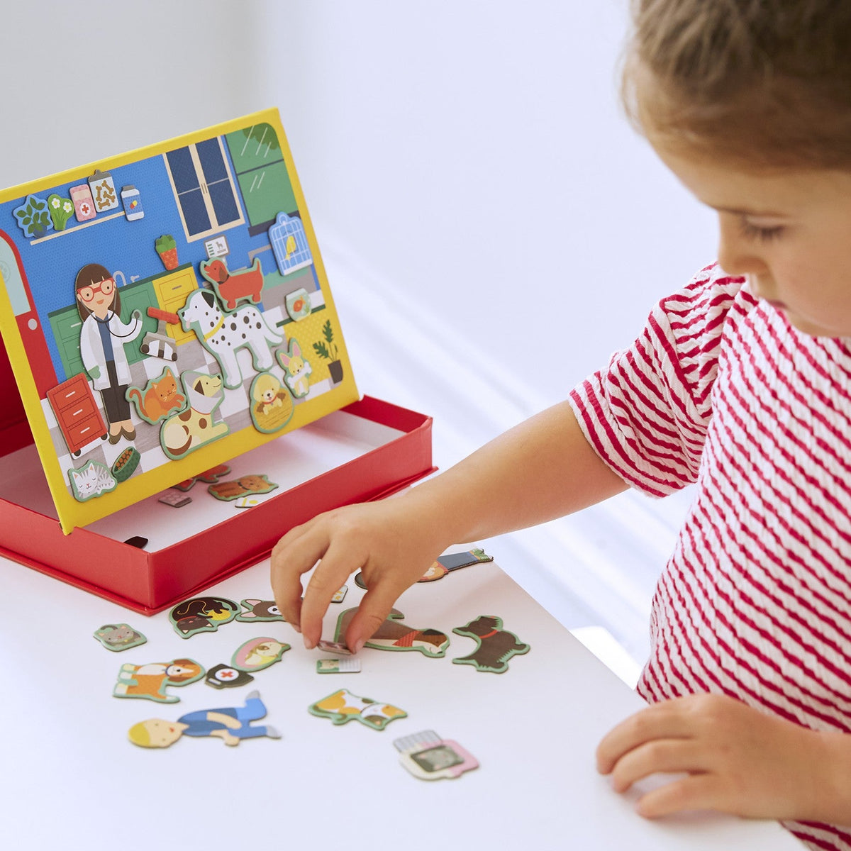Child playing with a puzzle set on a white surface