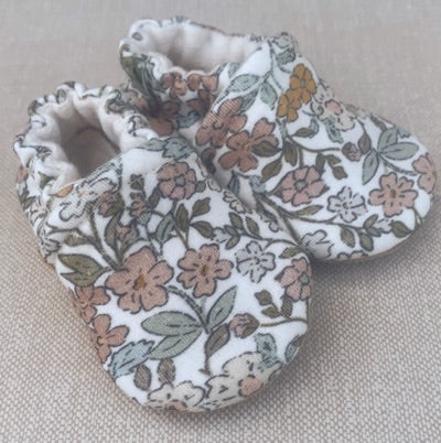 Floral-patterned baby shoes on a beige surface