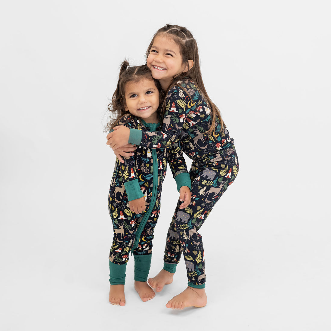 Two children wearing matching pajamas with animal prints on a white background