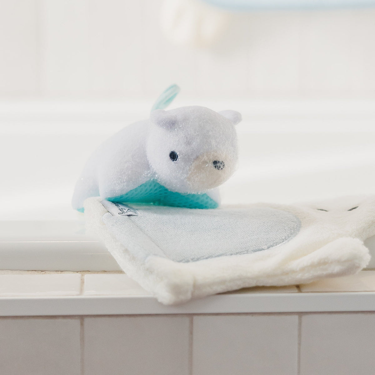 Plush toy resembling a cat on a white towel with a tiled bathroom background