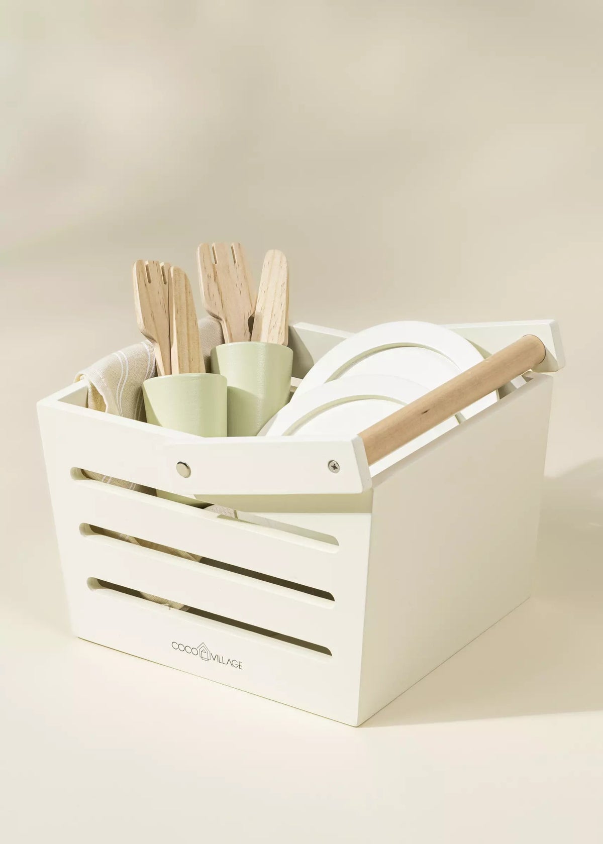 White storage crate with kitchen utensils including spatulas and a rolling pin on a beige background.