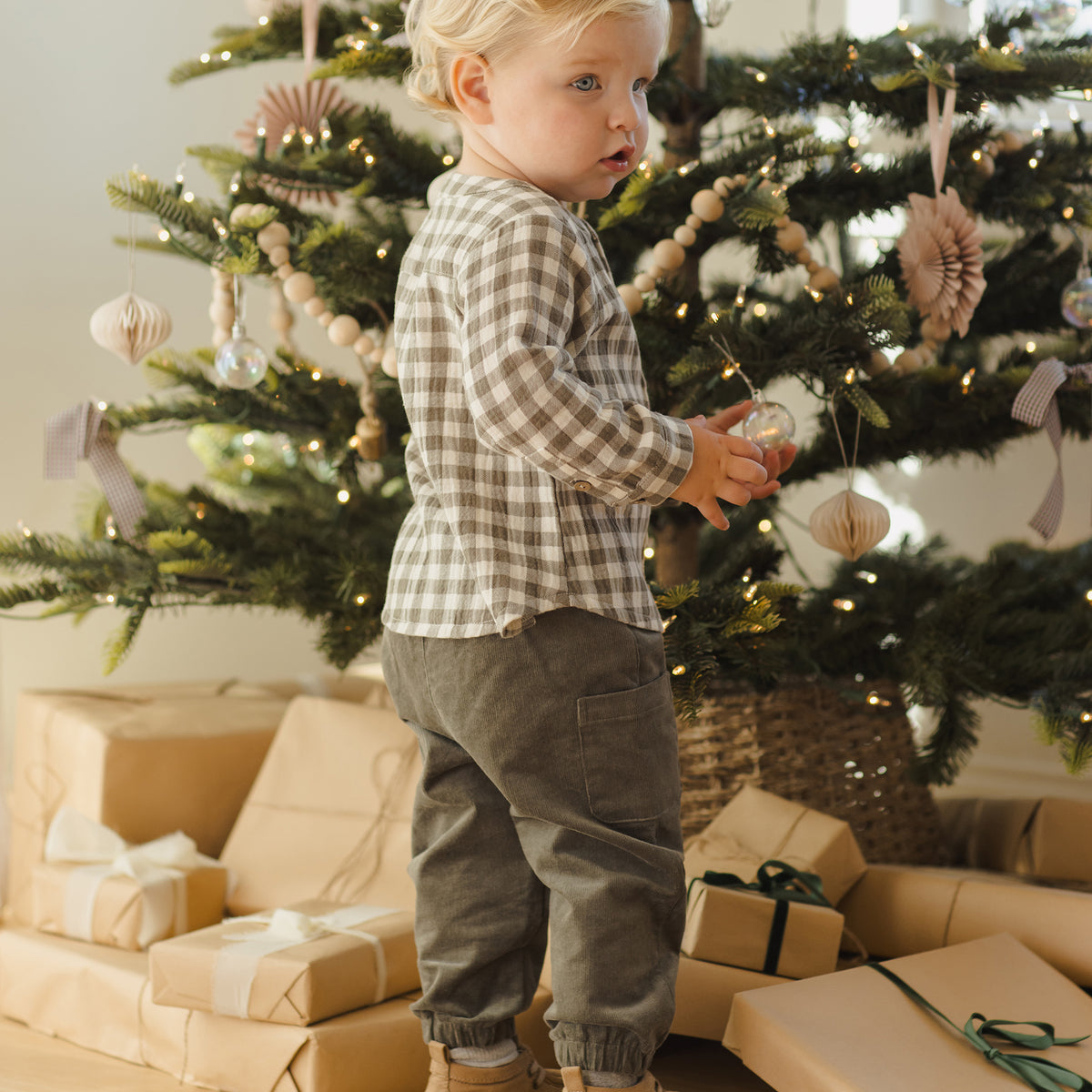 Child standing in front of a decorated Christmas tree with presents underneath