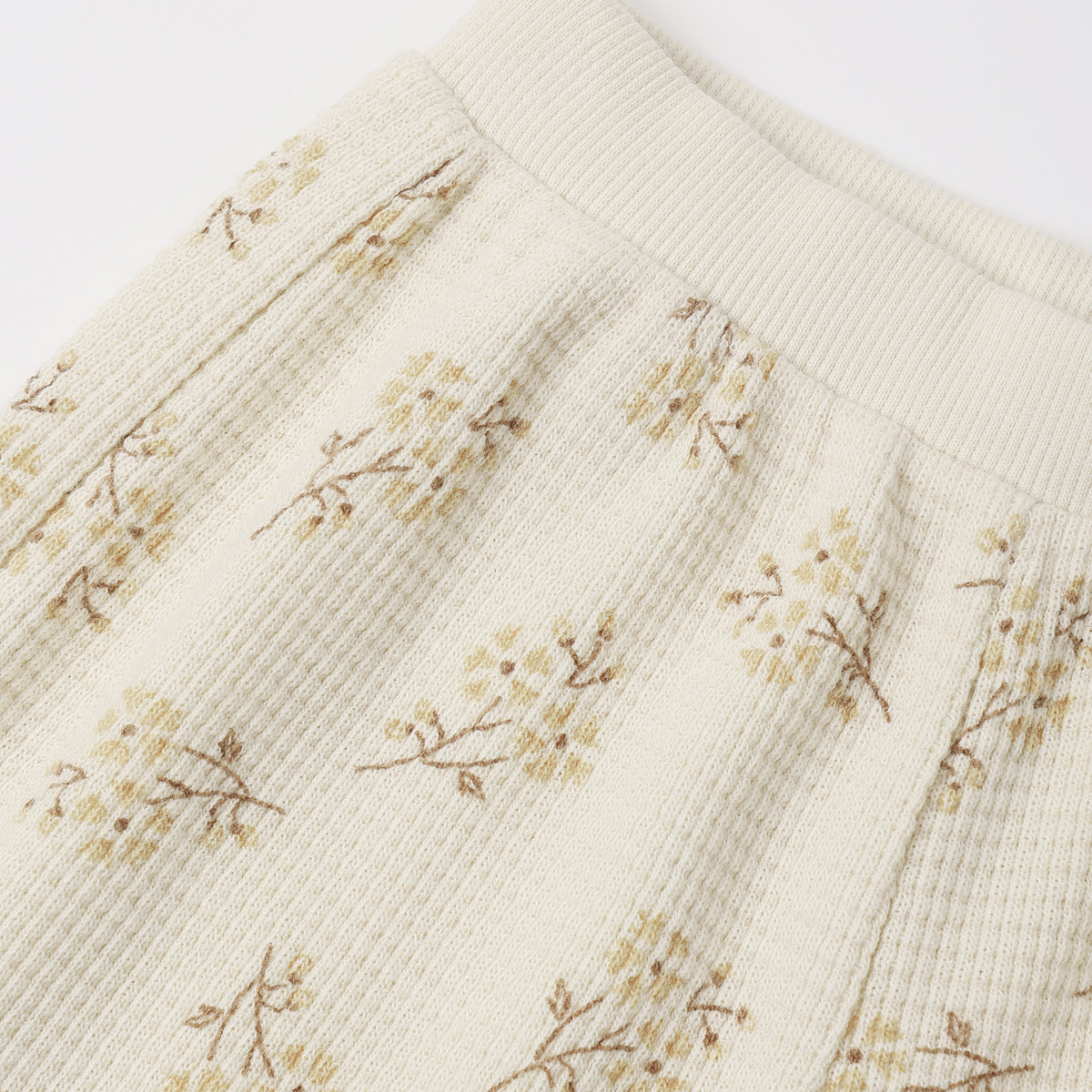 An off-white ribbed cotton toddler legging featuring a delicate, vintage-style small floral print with soft yellow and brownish stems.