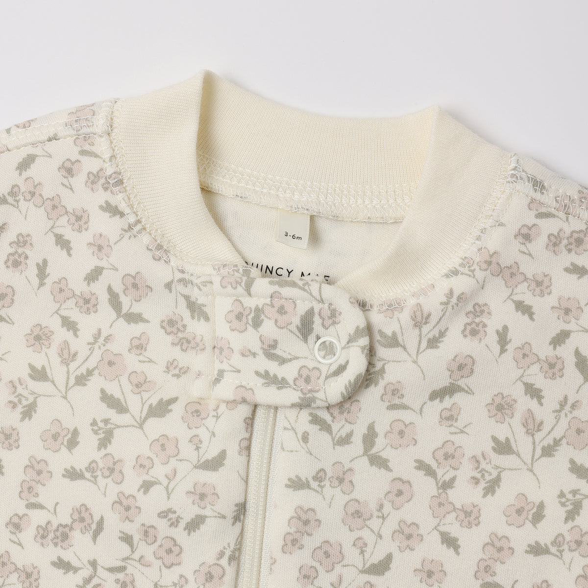Close-up of Quincy Mae Zip Long Sleeve Sleeper Footie in the "French Garden" print on an ivory background