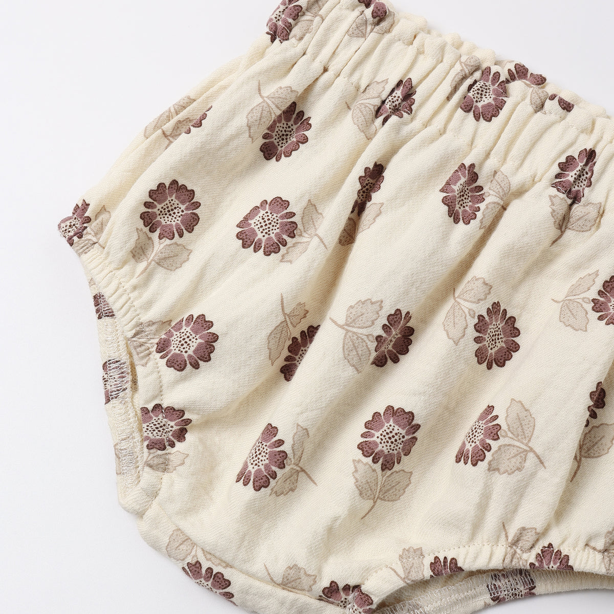Cream-colored cotton diaper cover with a brown and beige floral pattern, featuring an elastic waistband.