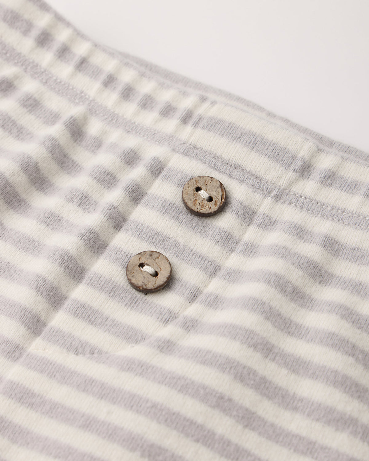 Close-up of the light gray and white fog stripe waffle knit fabric with two wooden buttons on the Quincy Mae Take Home Set.
