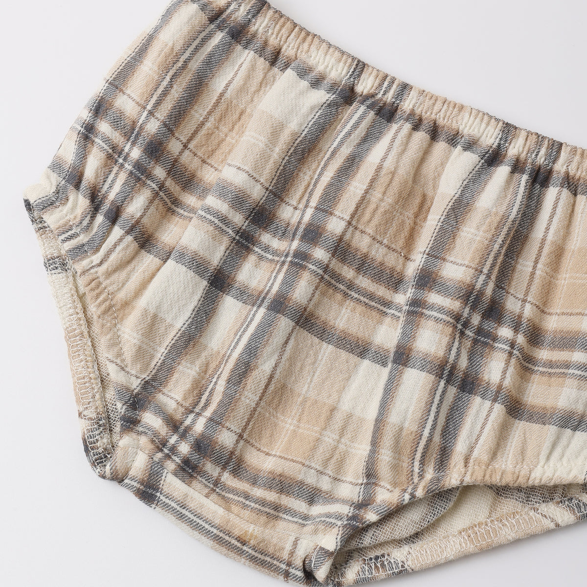 A pair of plaid baby bloomers in beige, brown, and gray, laid flat on a light gray background.