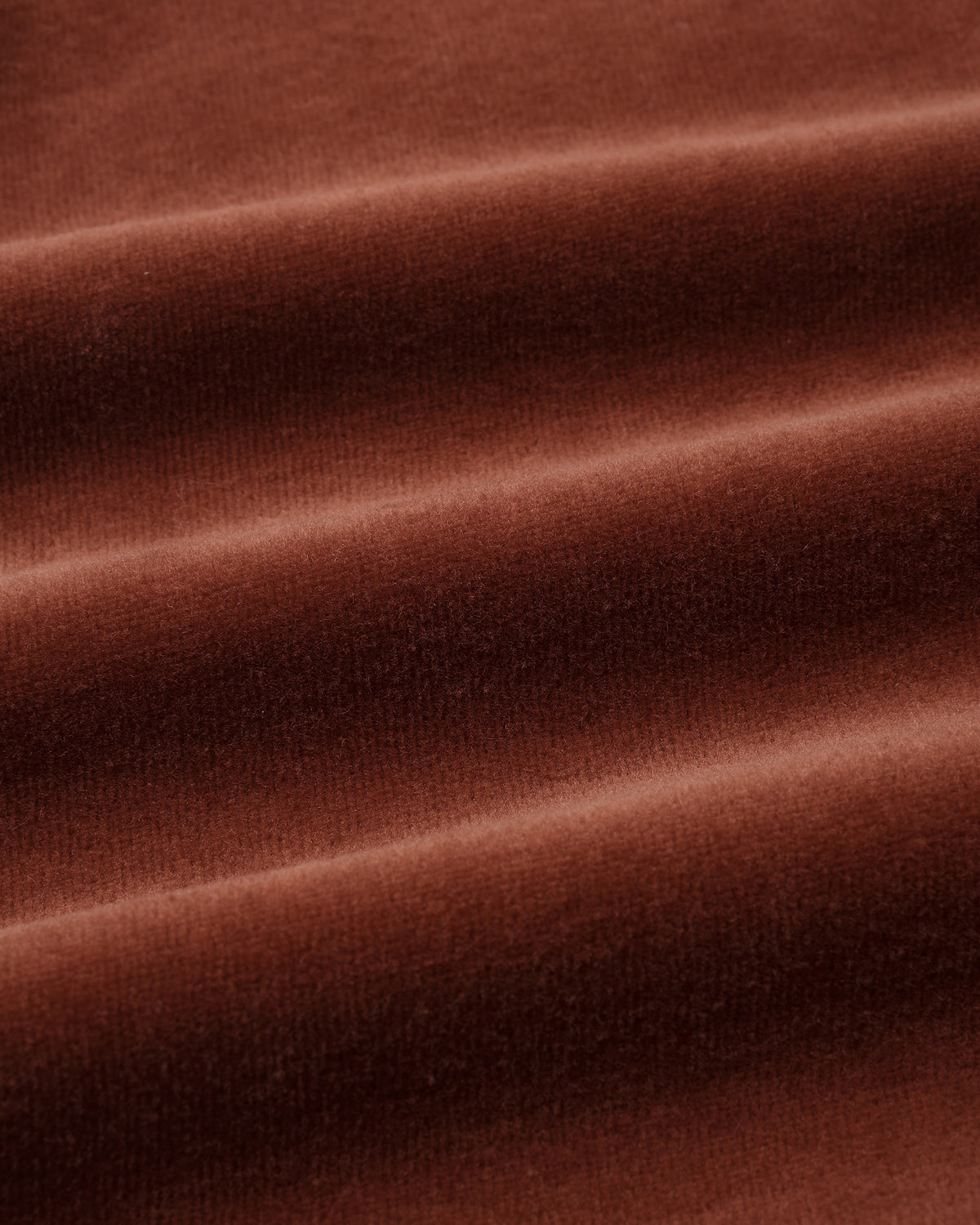 Close-up shot of soft, plush redwood brown velour fabric showing rich texture and gentle folds.