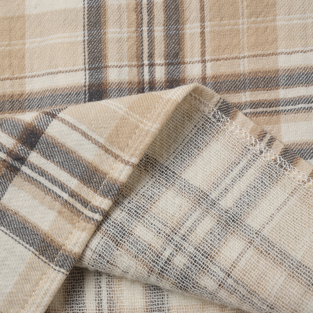 A close-up of a plaid fabric with a warm beige and cream base, accented by brown and gray stripes.