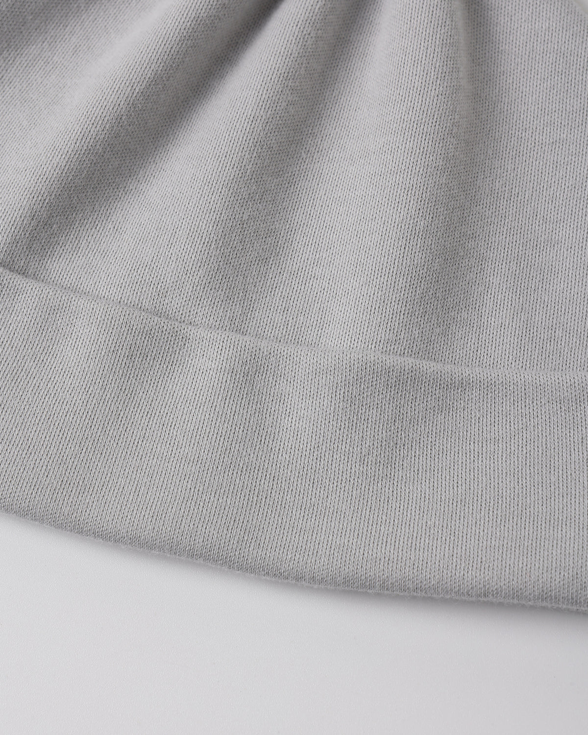Close-up of a light gray ribbed knit fabric, showing the texture and folded edges of a garment or textile.