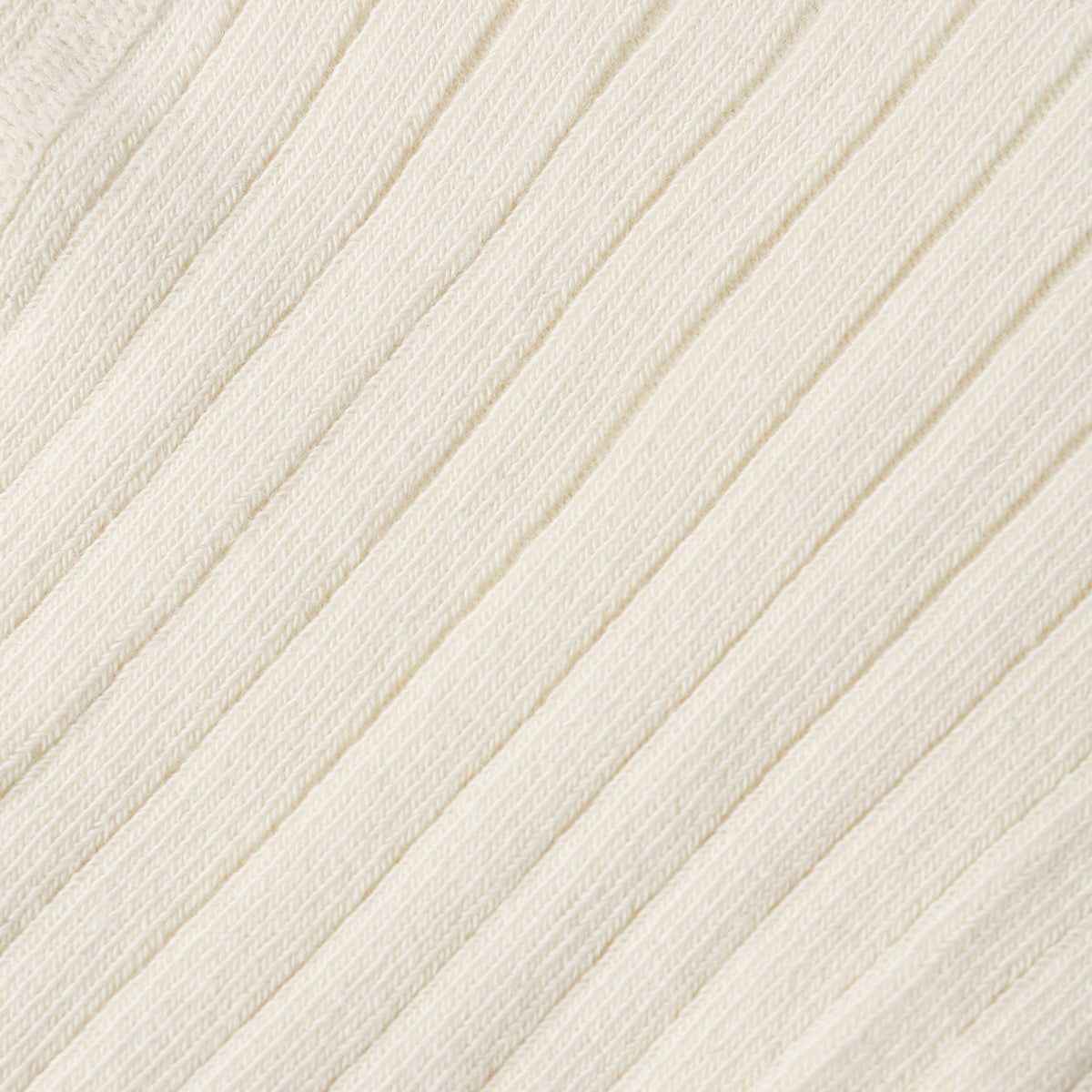 Close-up of a cream-colored ribbed knit fabric texture.