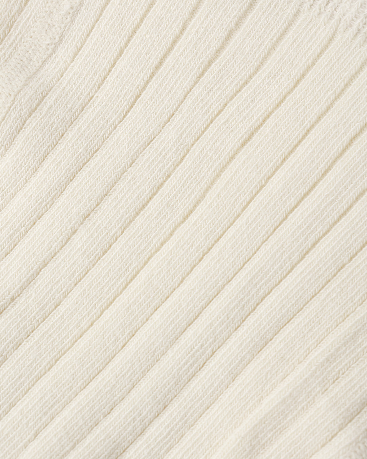 Close-up of a cream-colored ribbed knit fabric texture.
