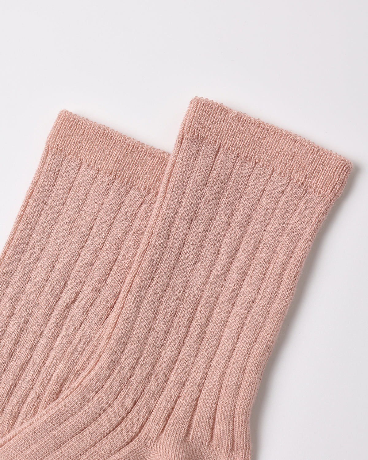 A close-up of a pair of ribbed ankle socks in a soft dusty pink color, showing the knit texture and cuff details against a clean white background.